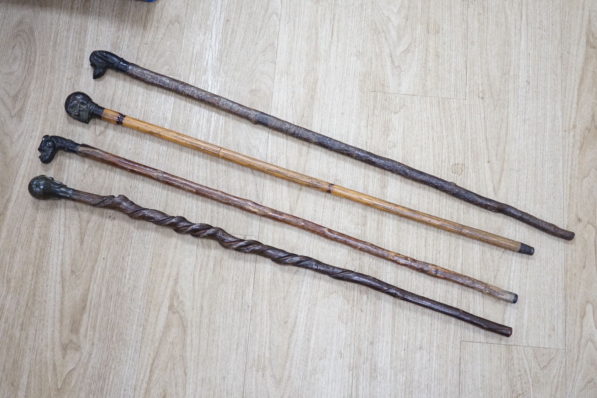 Four bronze topped walking canes, two with skulls, and two with dogs, canvas longest 93cm. Condition - fair to good.